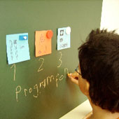 Kind schreibt sein Programm an die Wandtafel